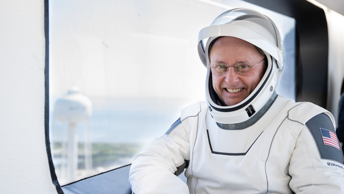 Um astronauta dentro da ISS olhando para a Terra.