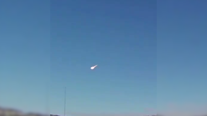 Um meteoro brilhante cruzando o céu noturno, deixando um rastro luminoso.